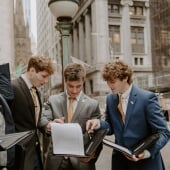 Two students and a professor stand outside the Academic Office Building.