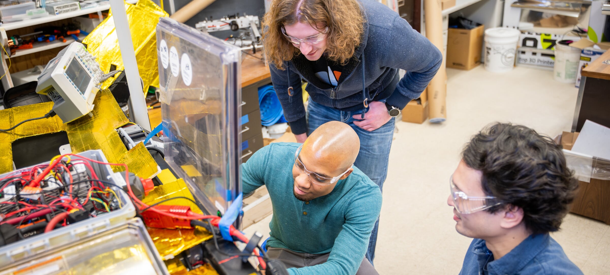 Students in a lab working on a satellite.