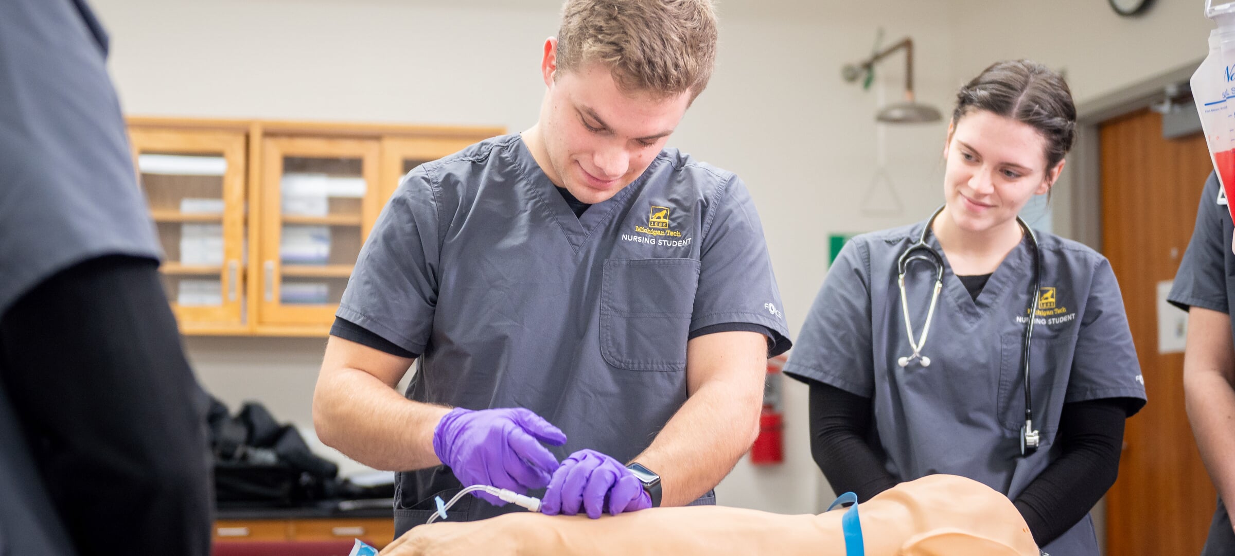 Pre-Health Professions students in lab coats holding different objects with some interacting with student patients