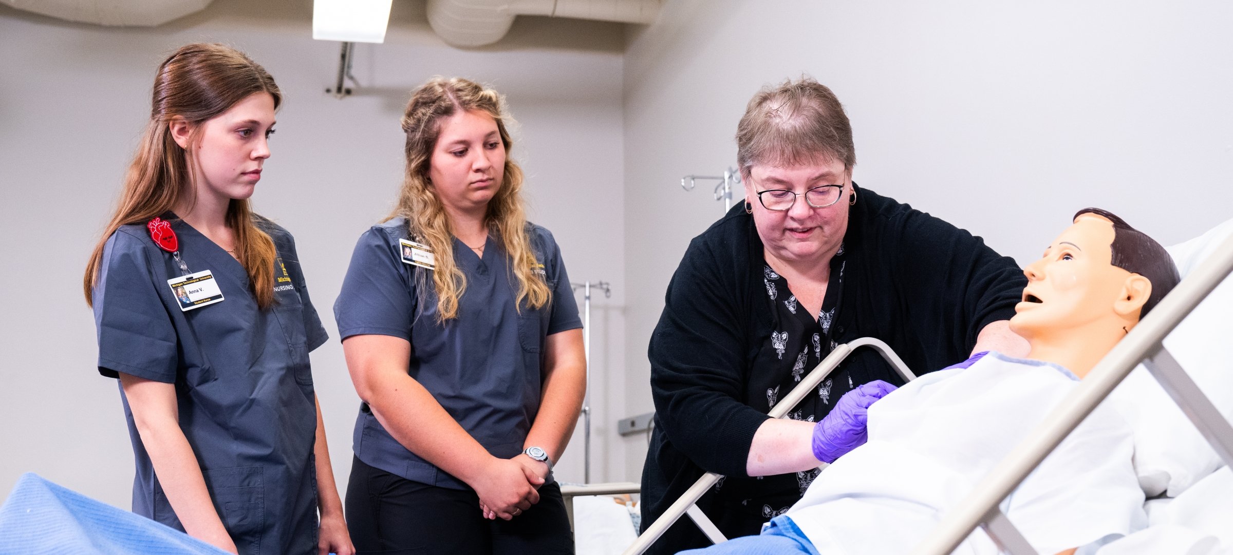 Nursing students observing an instructor with a mannequin patient