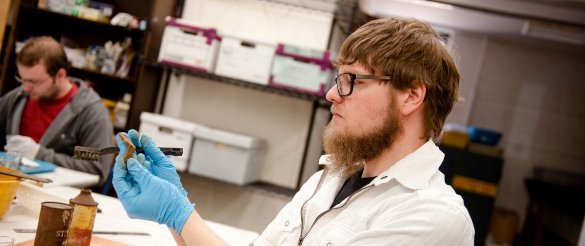 Student working with wood sample in a lab.