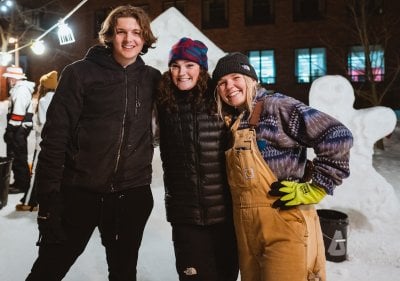 Students standing in front of a winter carnival statue