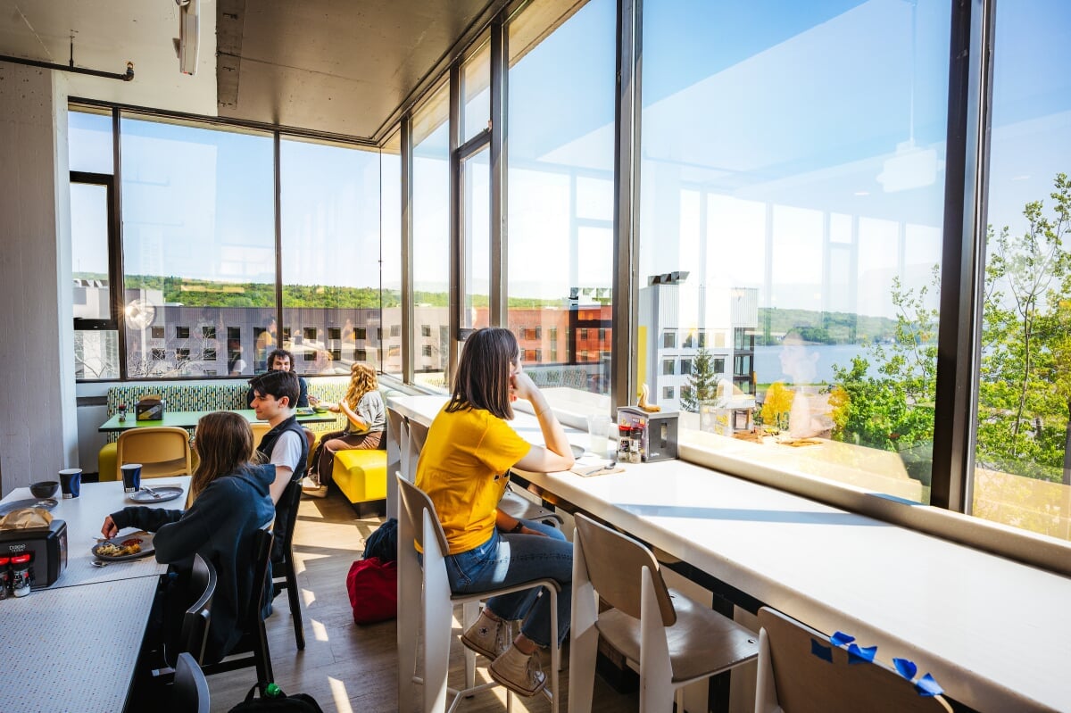 Students eating near a window overlooking East Hall and the Keweenaw Waterway