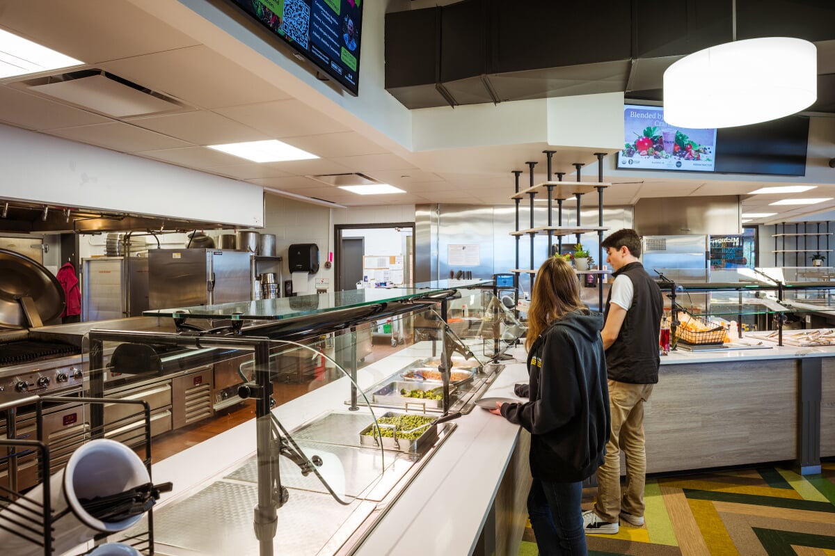 Students selecting food from a buffet area.