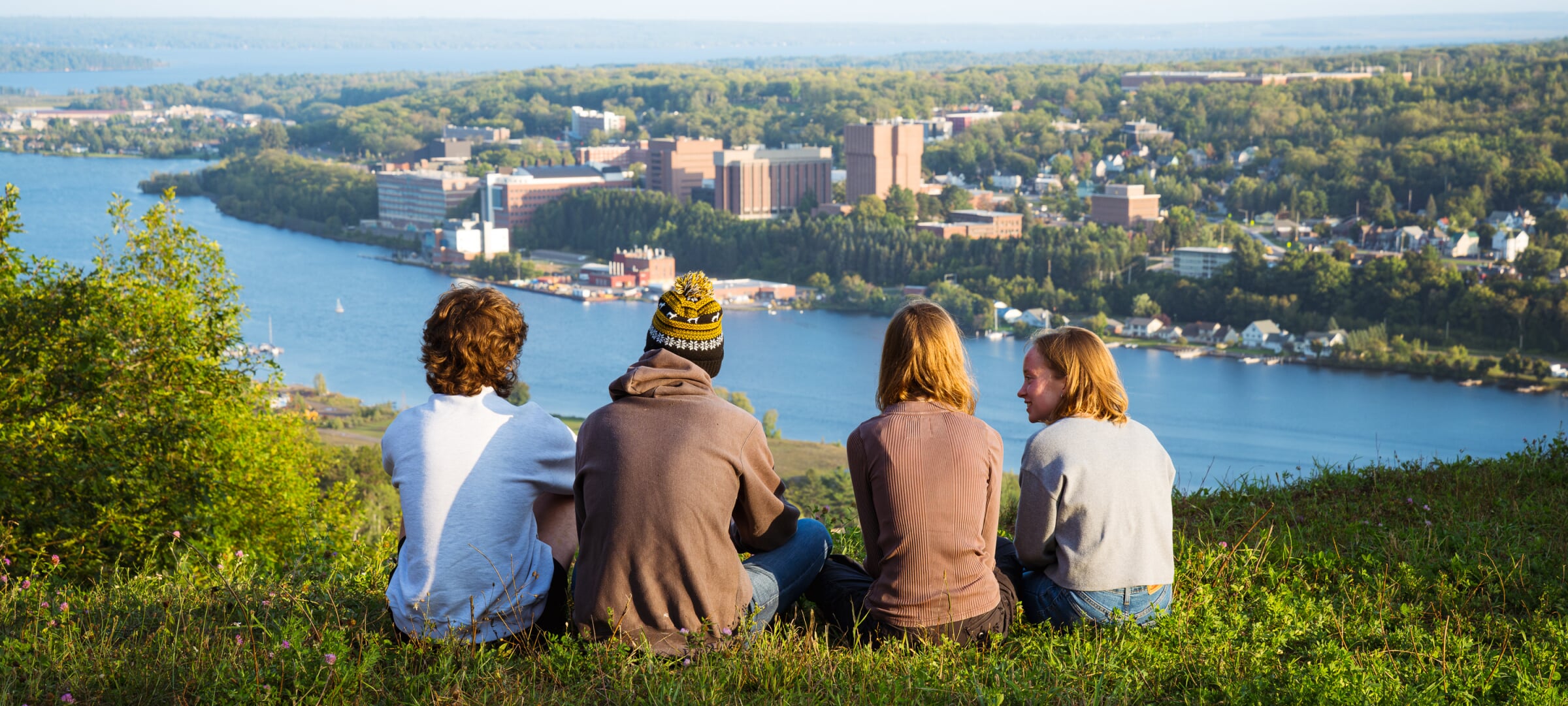Students sitting on the top of Mont Ripley overlooking Portage Canal and MTU campus.