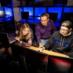 Professor teaching 2 students in computer lab