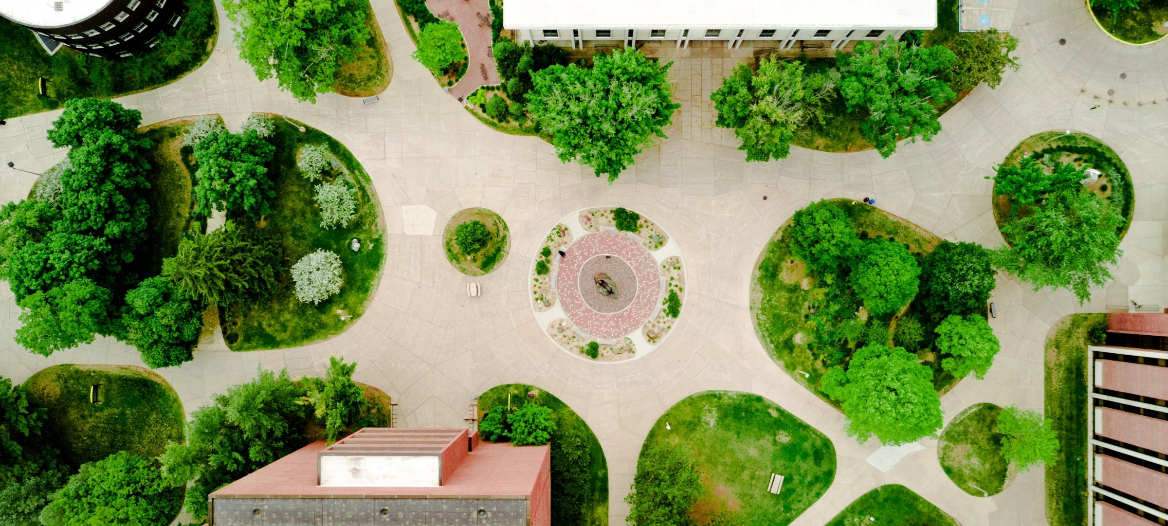 An aerial view in summer of the Husky Plaza on Michigan Tech's campus including many trees and the tops of several buildings.