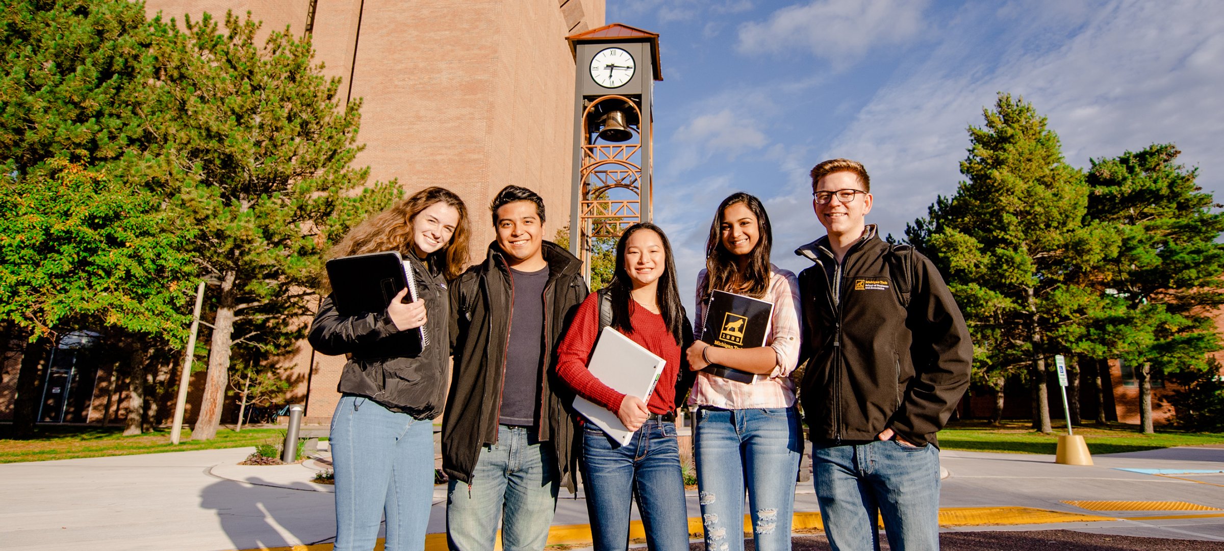 College of Business students on campus in front of the William J. Bernard Jr. Family Clock Tower and the Mechanical Engineering-Engineering Mechanics Building