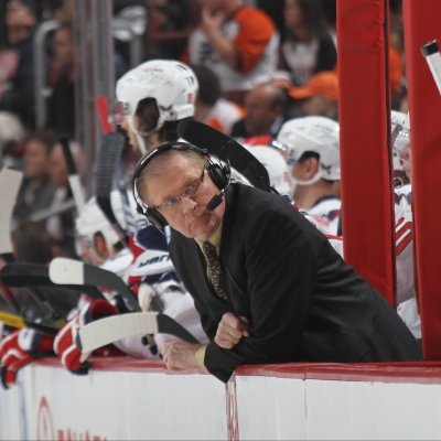 Steve Coates leaning over the ice ffrom the players bench.