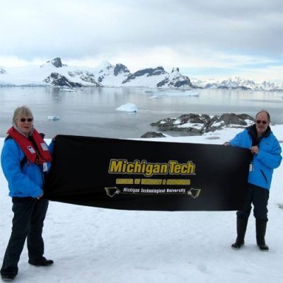 Tom and Mimi in Antartica holding a tech flag