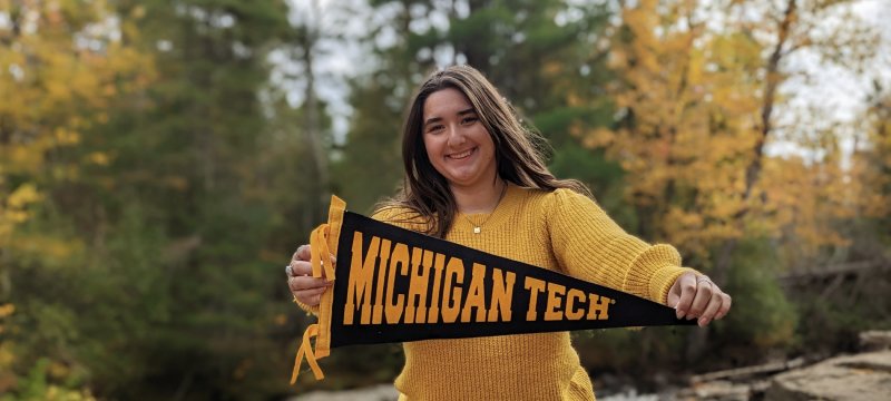 Ruby Walker holding a Michigan Tech pennant.