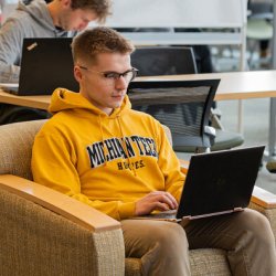 Henry Basala sitting in a chair with a laptop.