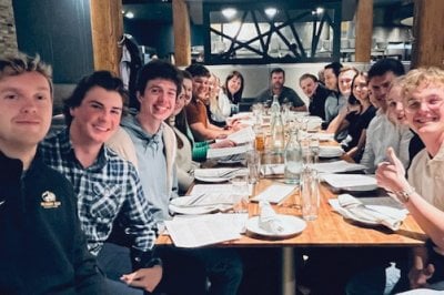 The two teams sitting around a set table.