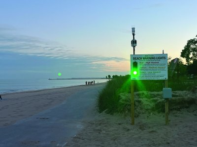 Beach with a sign saying Beach Warning Lights with small text descibing the light colors and a bright green light.