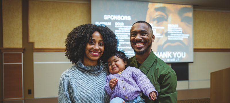 Jaylyn Boone standing next to his wife and holding his baby daughter.