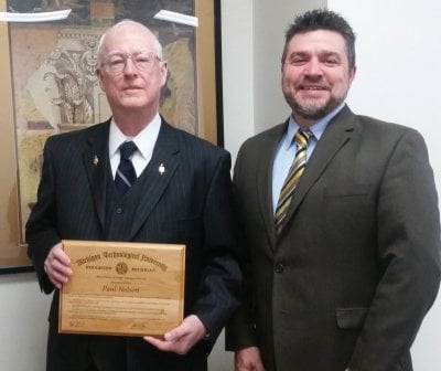 Paul Nelson holding a plaque standing next to Dean Johnson.