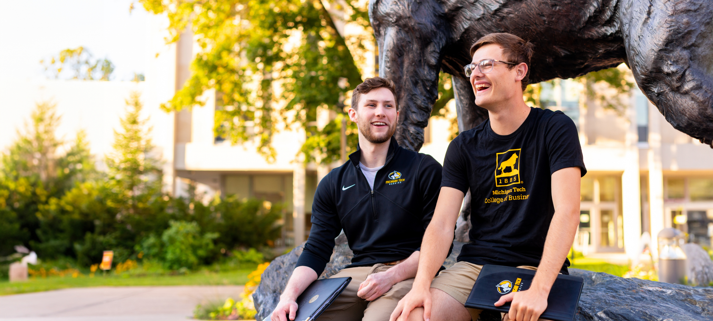 Students sitting near the husky dog statue