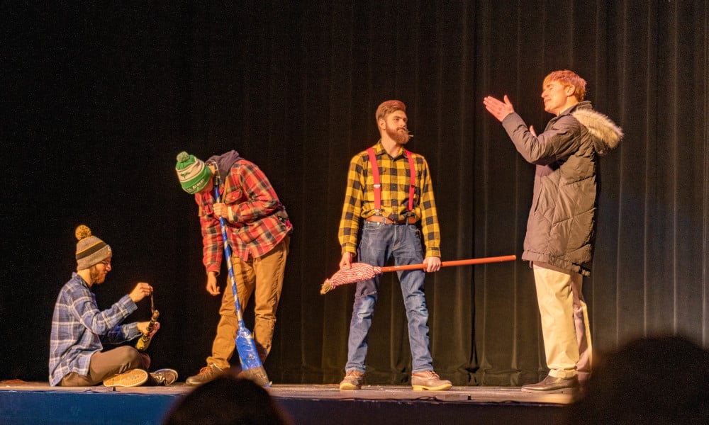 Performers on stage dressed in costumes in accusatory poses