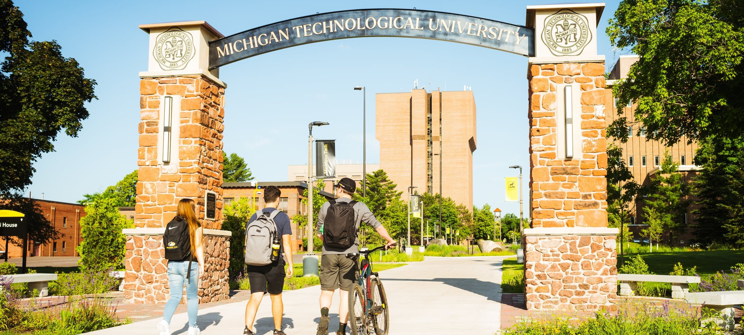 Three students walking through the alumni gateway arch
