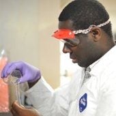 a man wearing a lab coat pouring chemicals. 