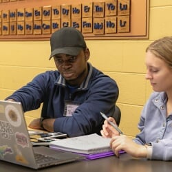 Black male tutor discusses a point with a white female student