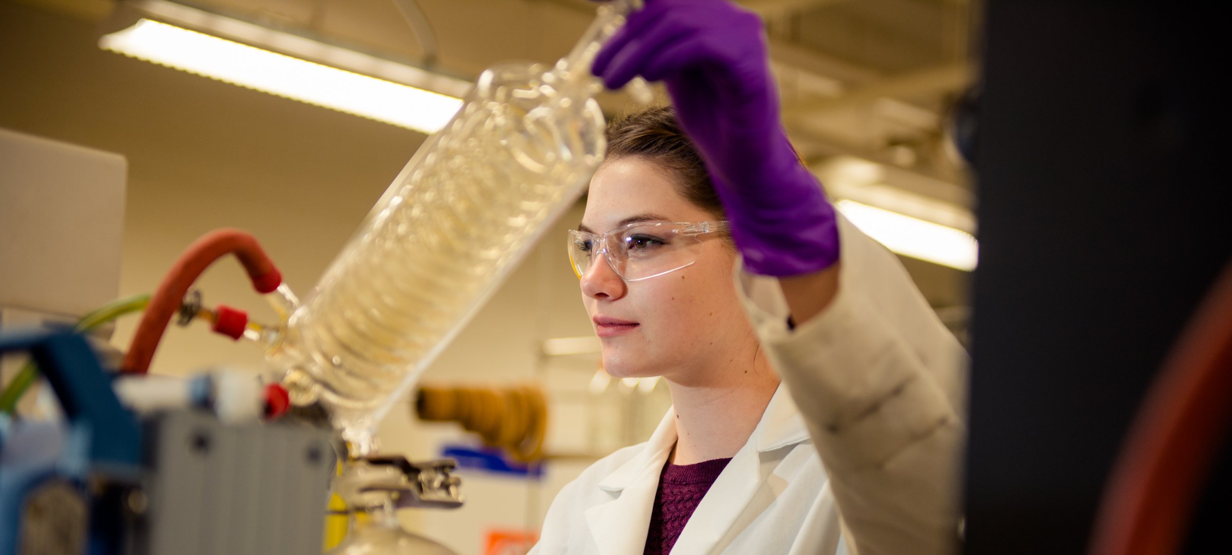 A person in a lab coat using chemistry equipment.