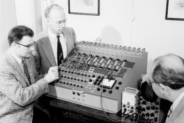 Three men working on a large computer circuit board