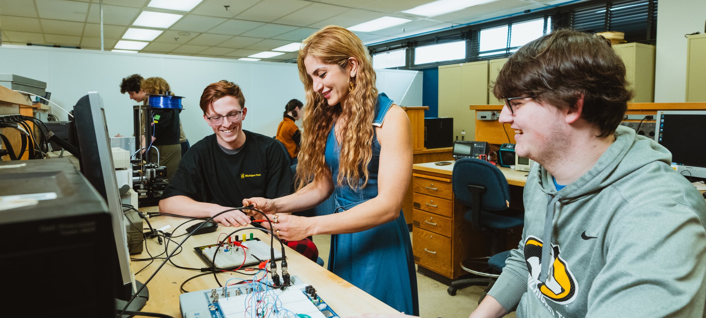 Two students with an instructor who's demonstrating lab work
