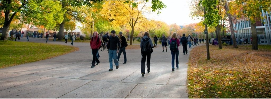 Students walking by Michigan Tech building Fisher Hall on a sunny fall day 