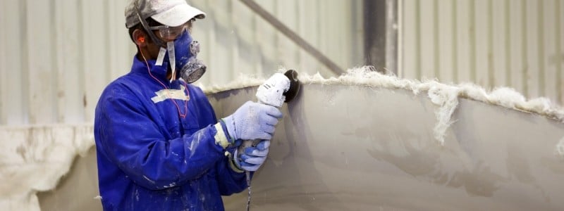 Worker wearing a respirator while using an angle grinder.