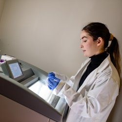 Researcher operating equipment with lab coat.
