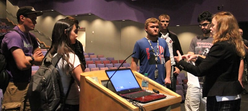 First-year engineering students approaching the speaker at the podium.