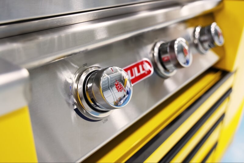 close up of the shiny silver knobs on the CTech Manufacturing grillcart in bright yellow with shiny chrome details and black wheels