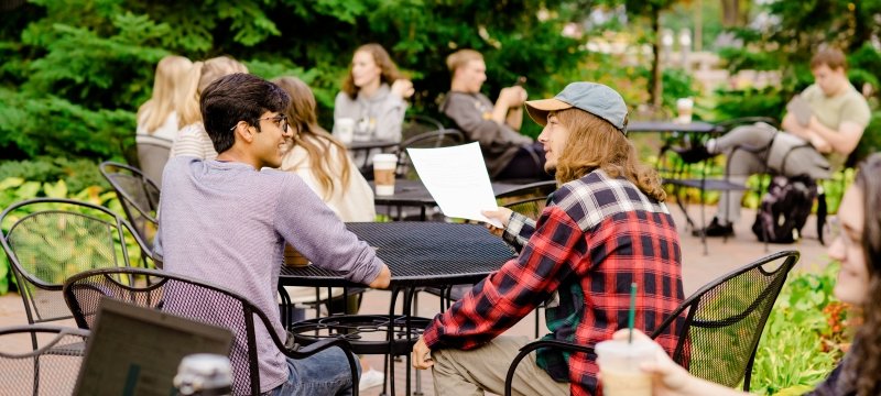 Undergraduate students chatting and studying outside with coffee