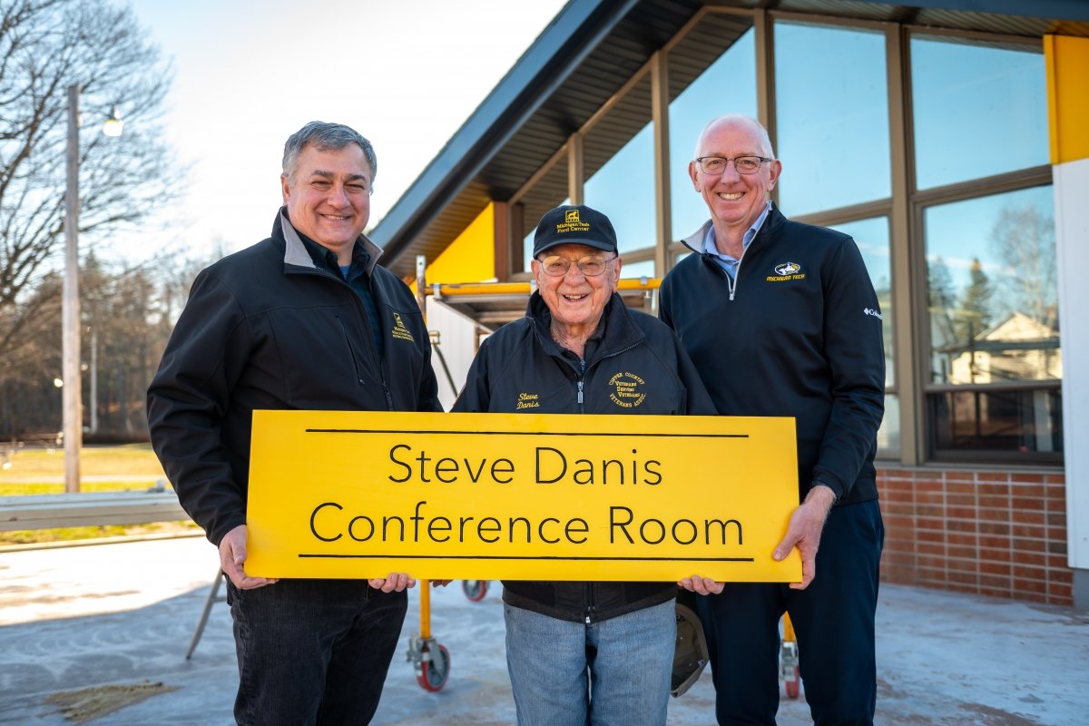 Mark Rudnicki, Steve Danis, and David Flaspohler (pictured left to right) holding a sign that reads &quot;Steve Danis Conference Room&quot;