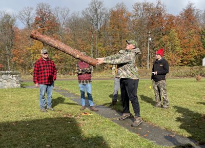 Person throwing a log while others watch.