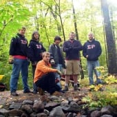 Sigma Rho members standing on a trail in the woods.