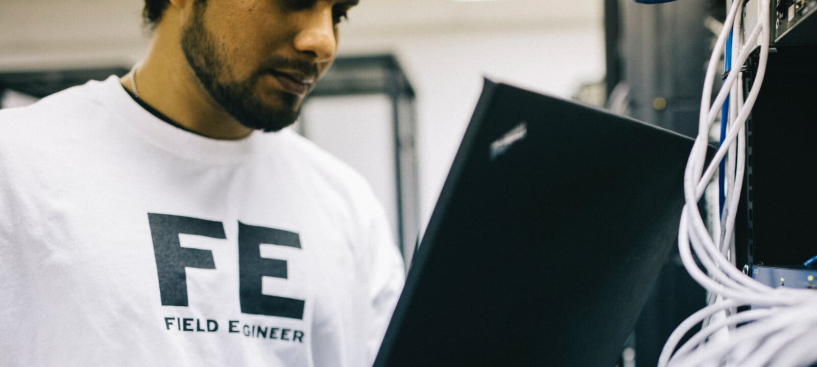 A field engineer with a laptop addressing a computing and electrical problem in a work environment.