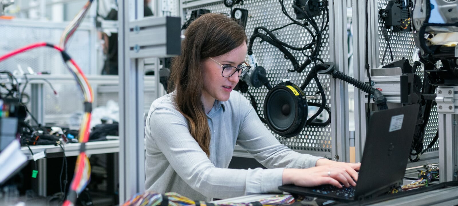 Young woman in a car parts workplace works on her laptop on an online program.