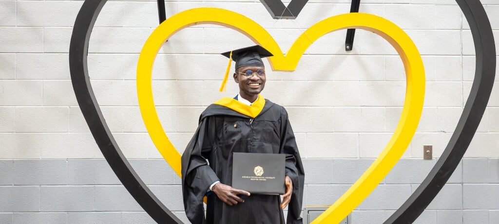 President Koubek and graduate student holding degree smiling for the camera.