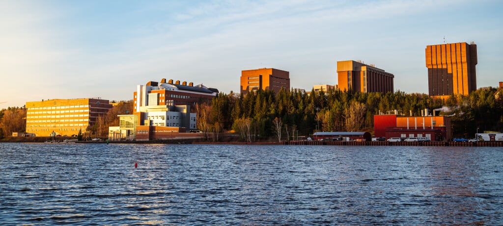 Bright, snowy campus from across the frozen water in morning light