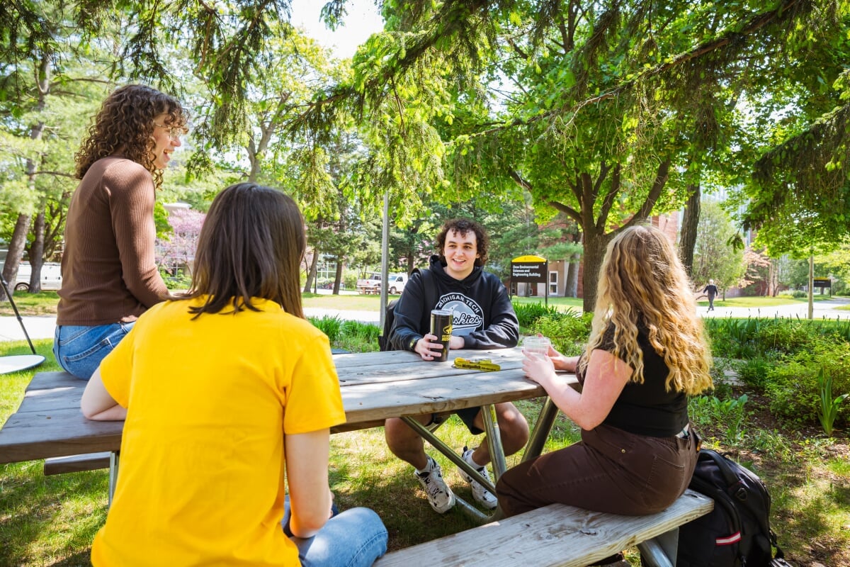 Schedule a campus tour and experience Michigan Tech for yourself. Students sitting outside at a picnic table.