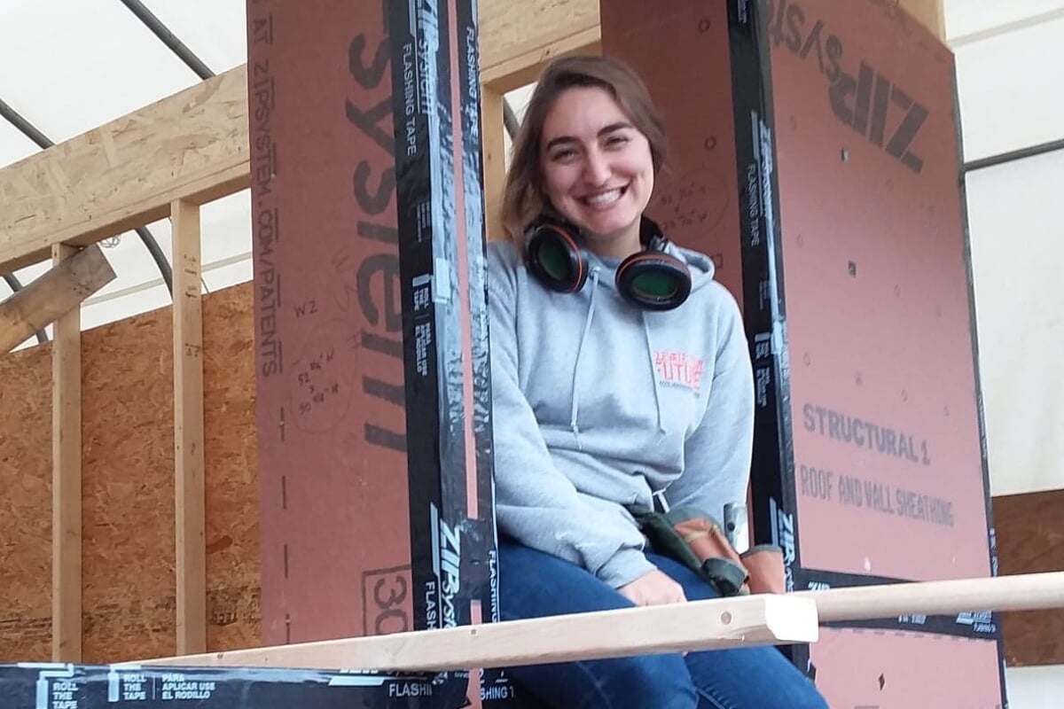 A woman sits on the framework of a building in progress