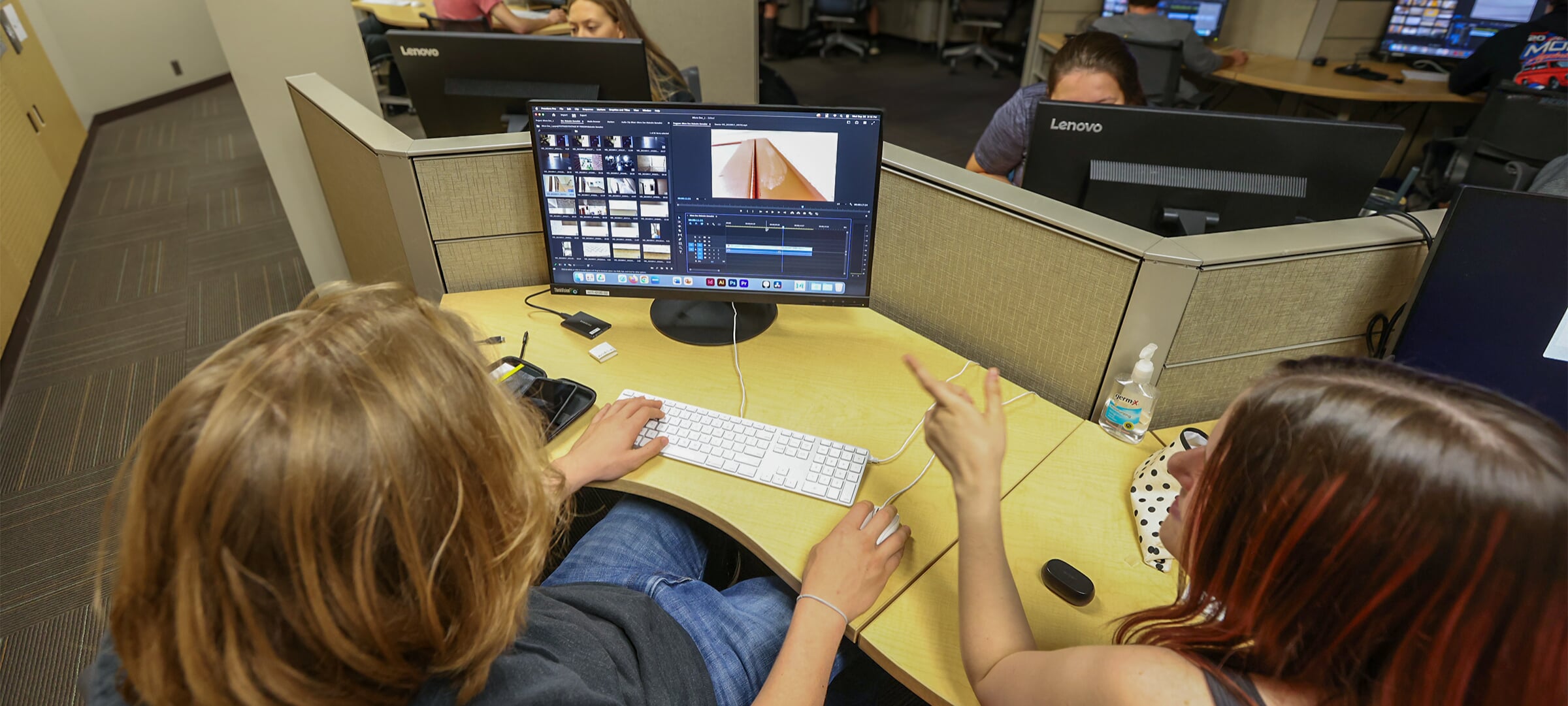 Two students collaborating on film editing at a workstation in the Humanities Digital Media Zone.