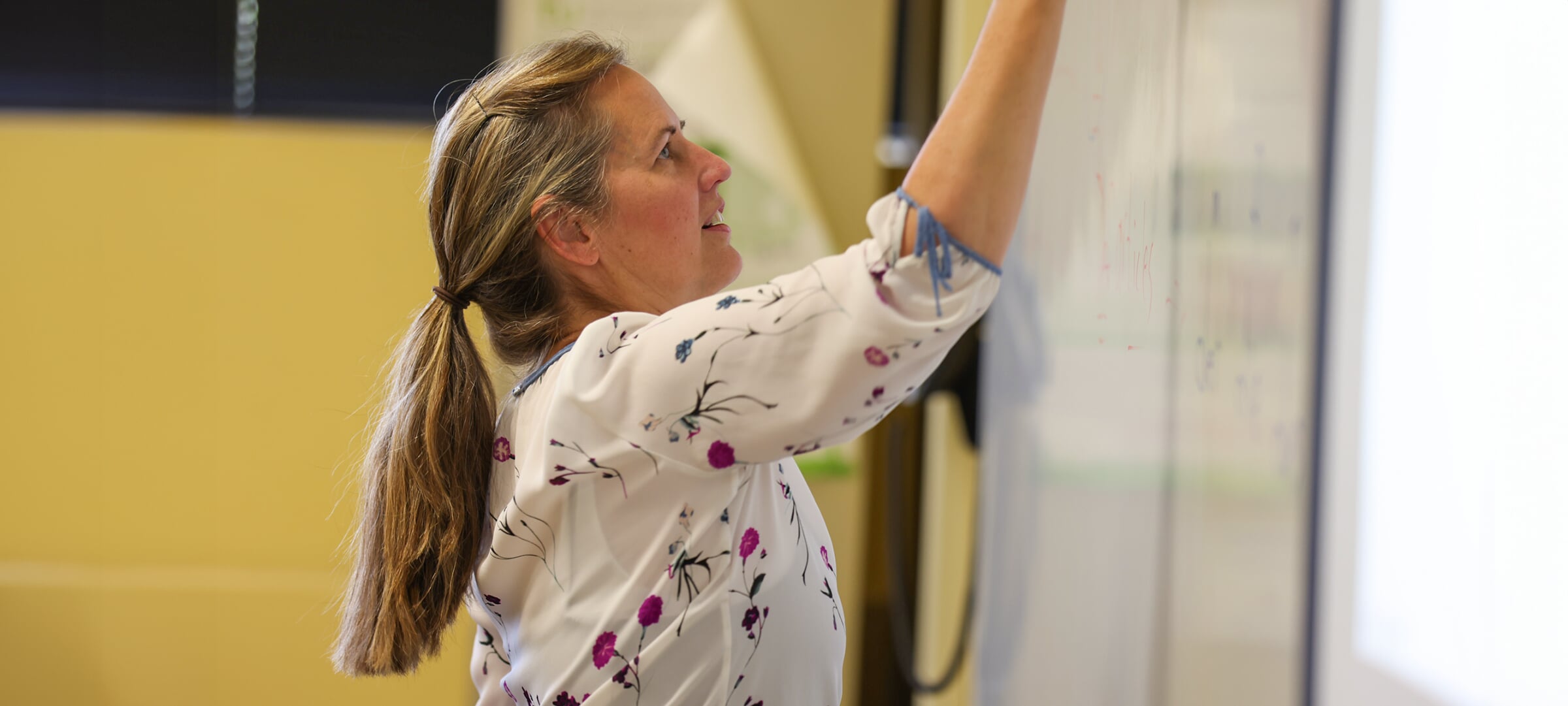 German professor Stephanie Rowe writes on a whiteboard during class.