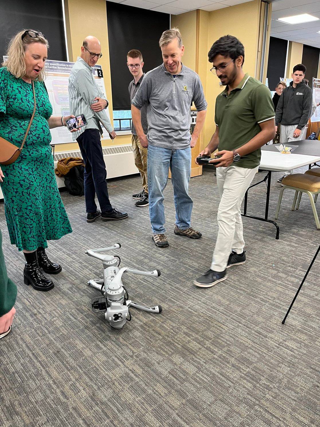 A robot dog goes off script during the Student Poster Competition and falls over. Luckily, Elizabeth Veinott (left) says her dog does that all the time, so it is perfectly normal. Poster Session Robot demonstration.