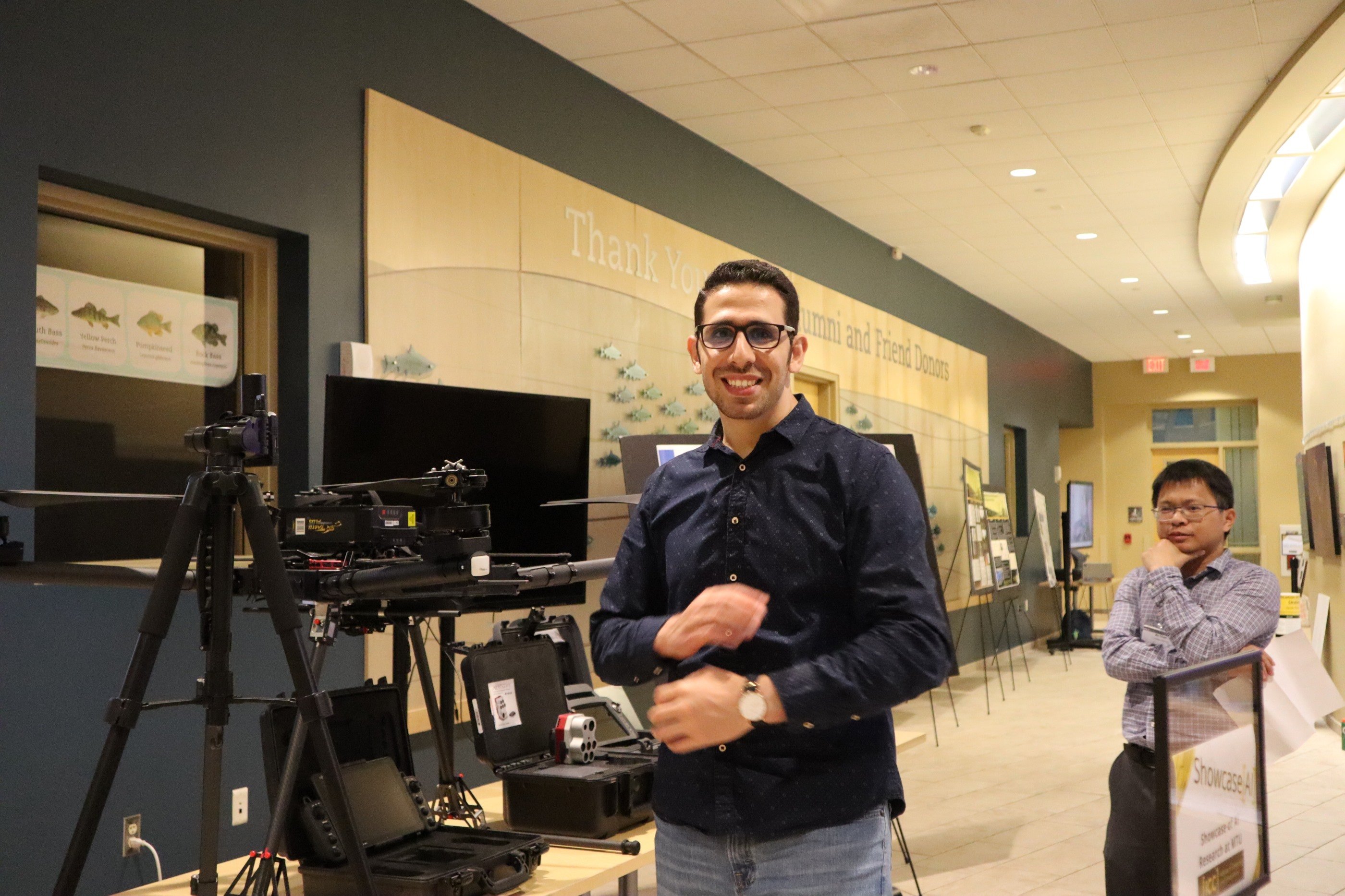 Ali Awad standing next to the Robotics and Remote Sensing Lab research display. Ali Awad.