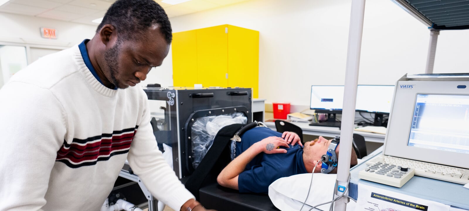 Researcher fixing a device onto a participant laying down.