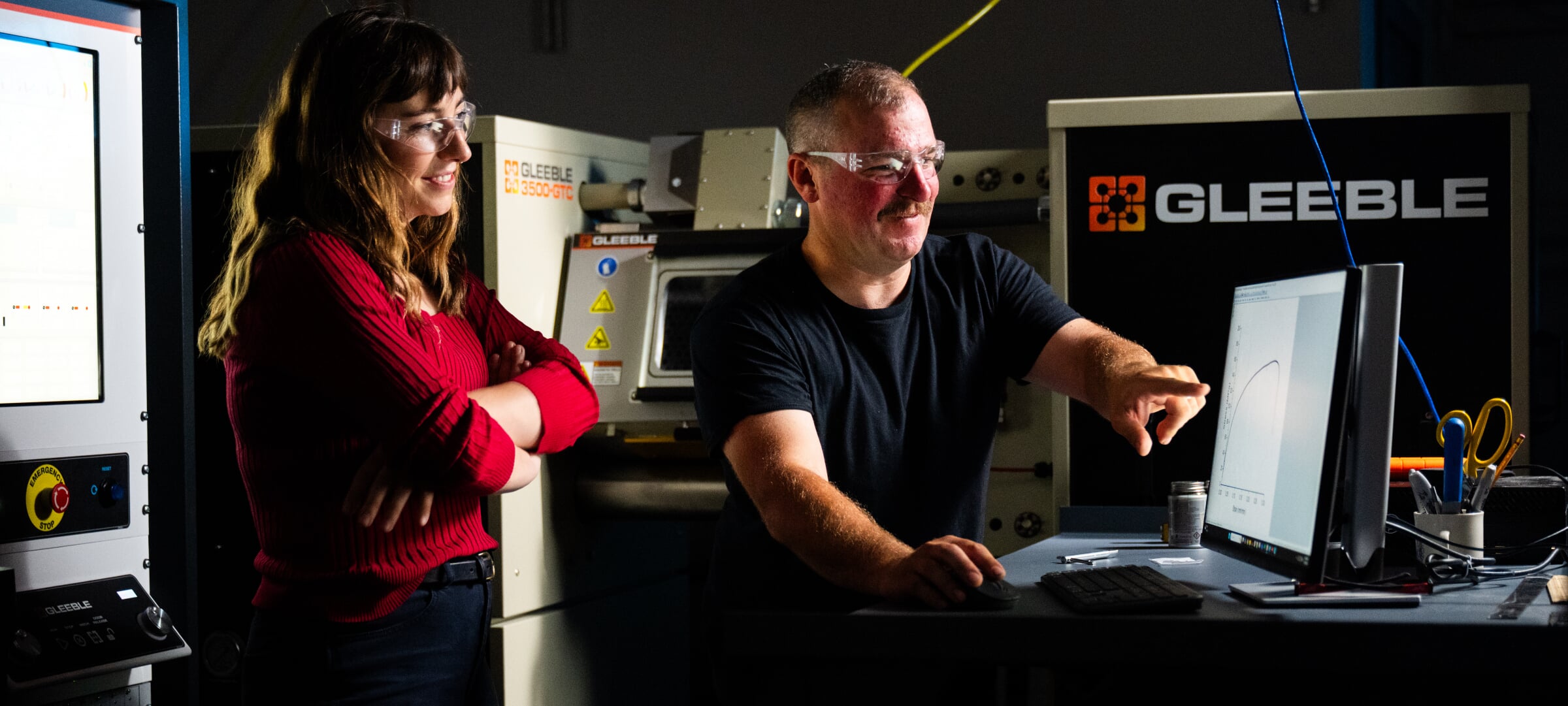 Two people looking at a computer with a chart on it.