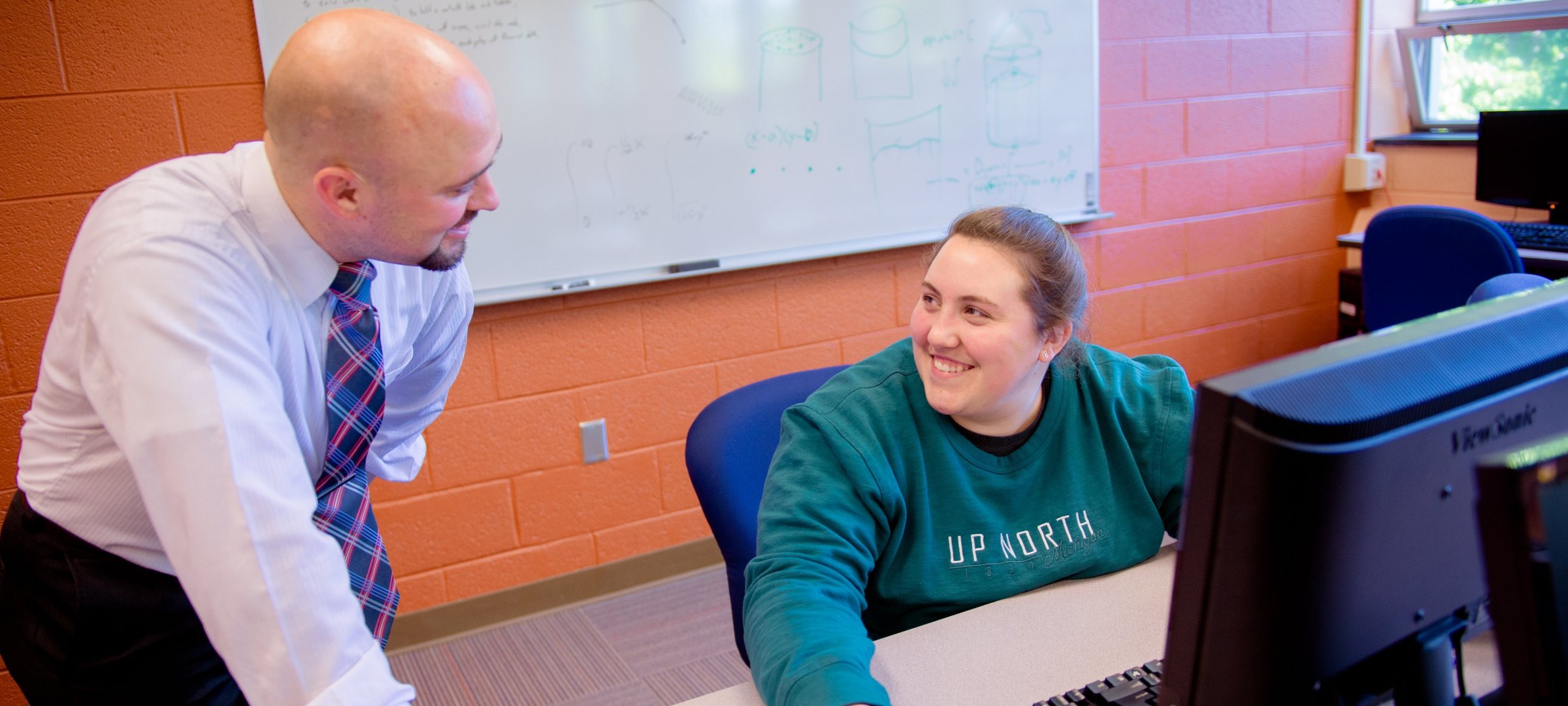 Faculty working with a student at a computer.